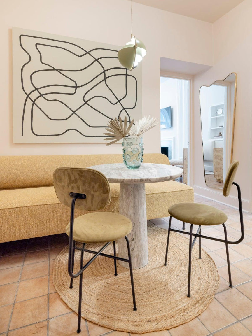 Modern dining area with a beige sofa, round table, and chairs in a stylish room.