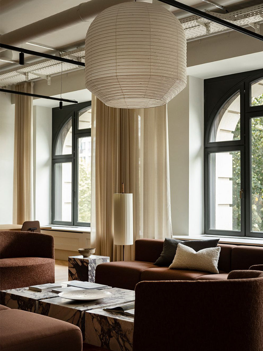 Modern living room with brown sofas, a coffee table, and large windows.