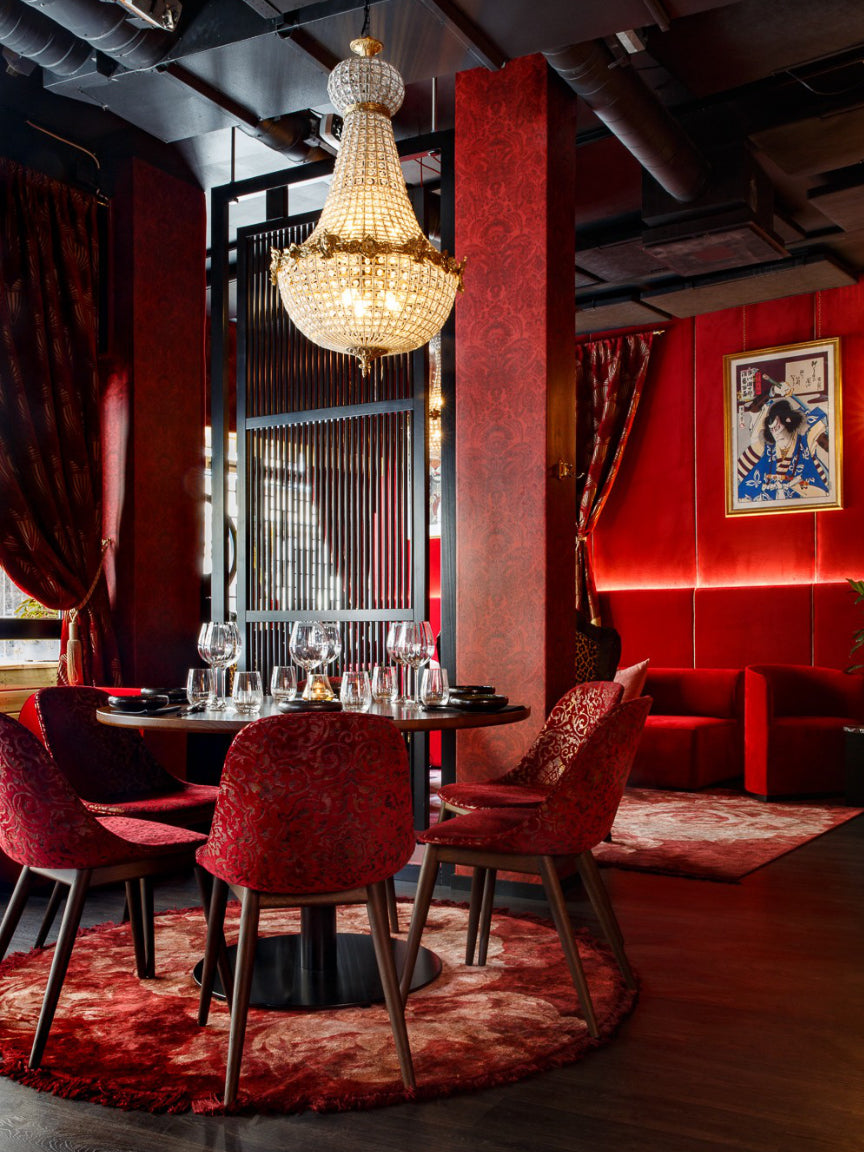 Luxurious interior with a chandelier, red chairs, and a table set for drinks.