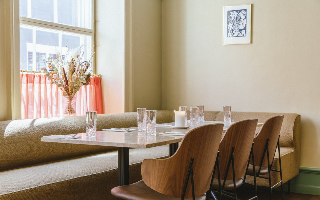 Dining area with a table, chairs, and a large window with pink curtains - Audo Copenhagen