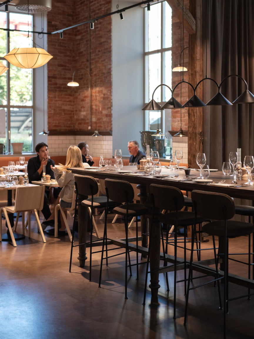 Dining area with tables, chairs, and people in a modern restaurant setting.