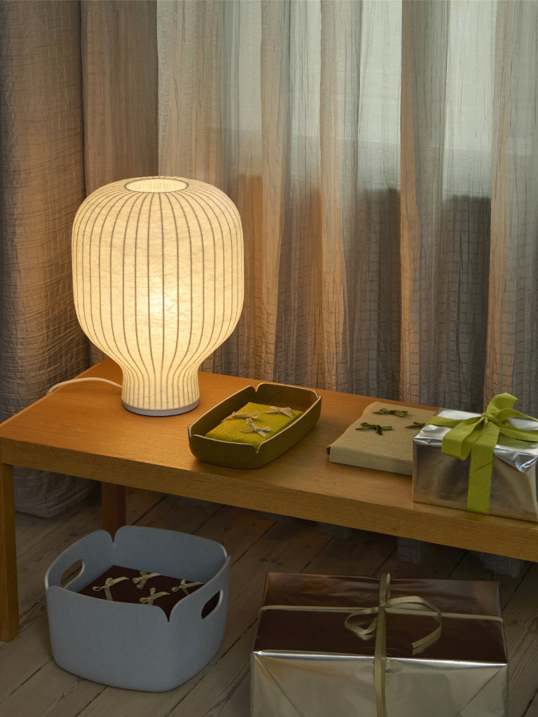 Table lamp on a wooden table with decorative items and curtains in the background