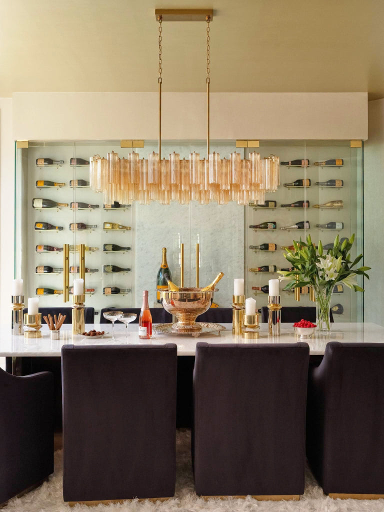 Dining room with a chandelier, wine bottles on shelves, and a table setting.