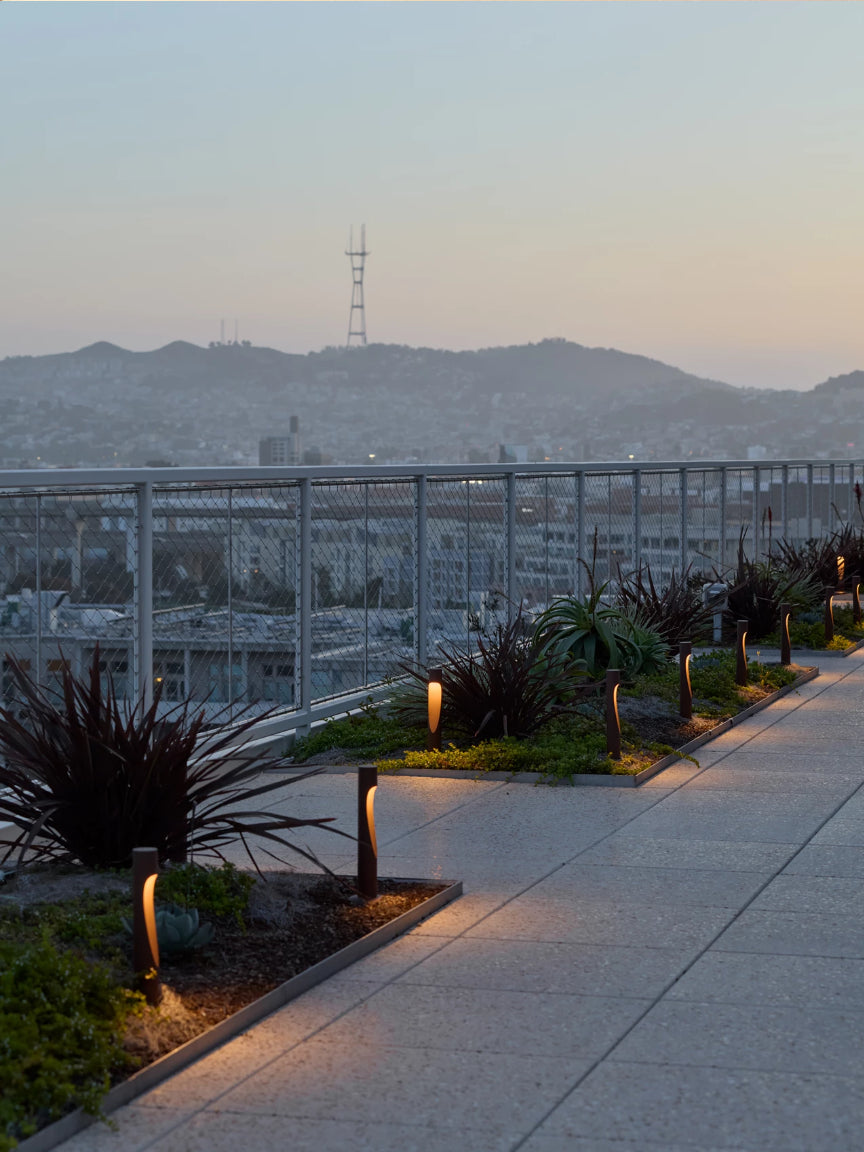 Cityscape with mountains in the background, illuminated by streetlights on a clear evening.