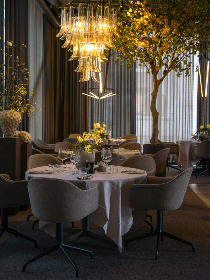 Modern restaurant interior with tables, chairs, and a decorative chandelier.