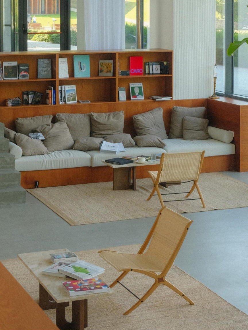 Modern living room with a sectional sofa, bookshelf, and chairs.