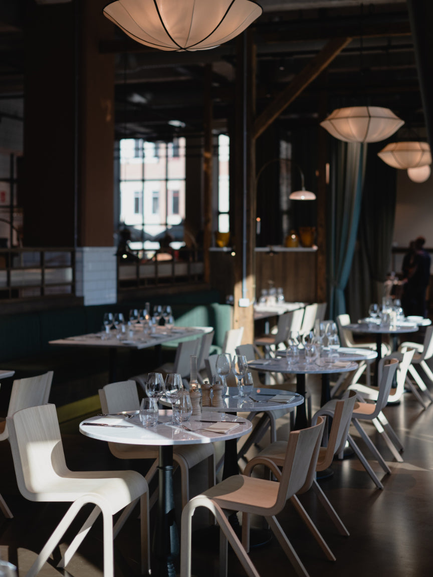 Modern restaurant interior with tables and chairs, dimly lit.