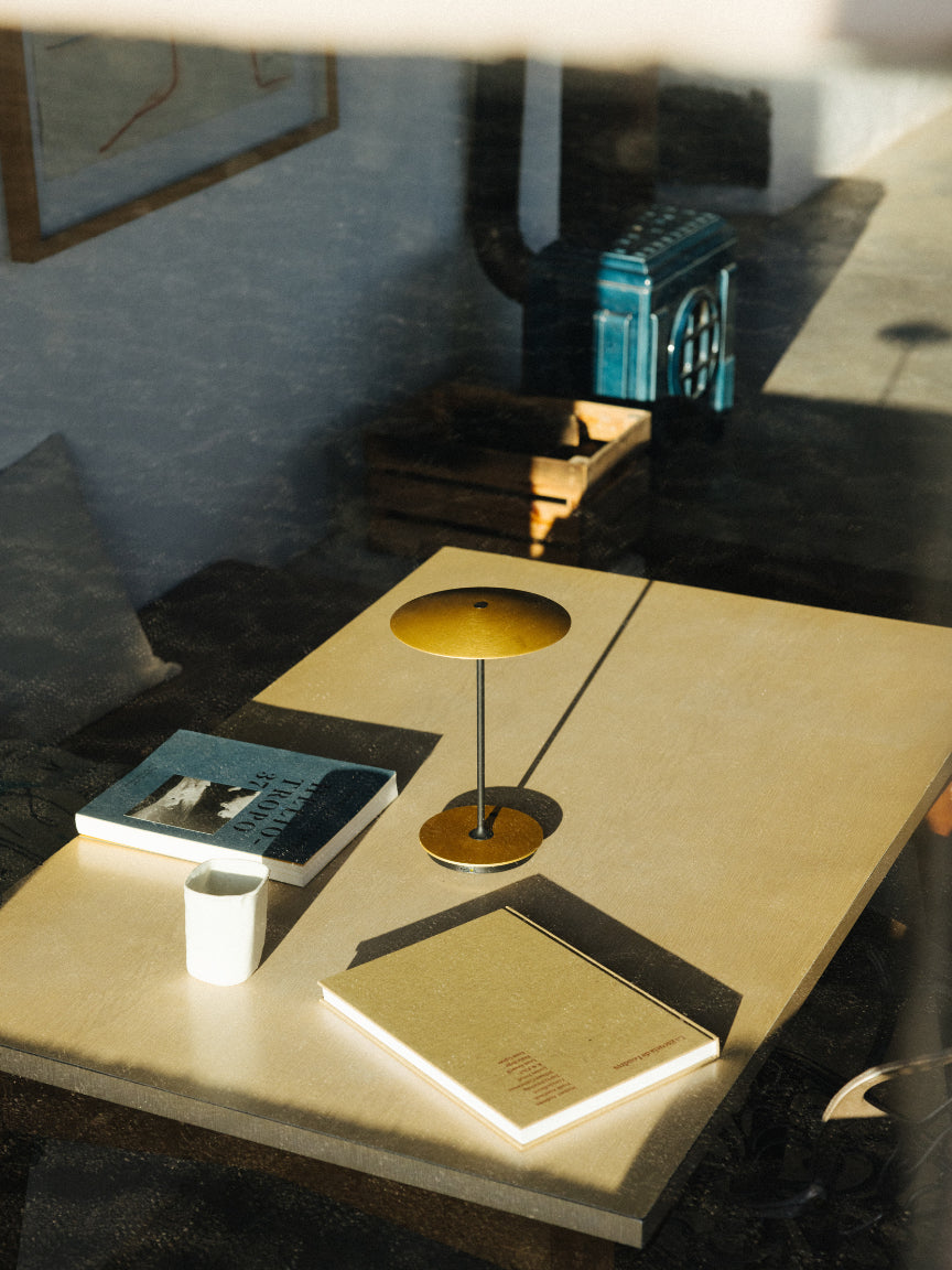 Modern interior with a table, lamp, and books in a dimly lit room.