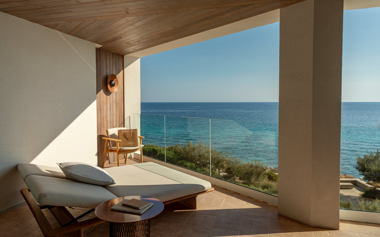 Modern patio with ocean view, featuring a lounge chair and table.