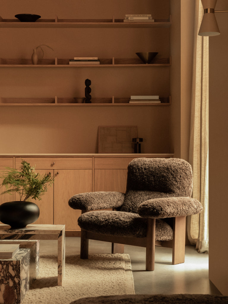 Modern living room with a textured armchair and wooden shelves.