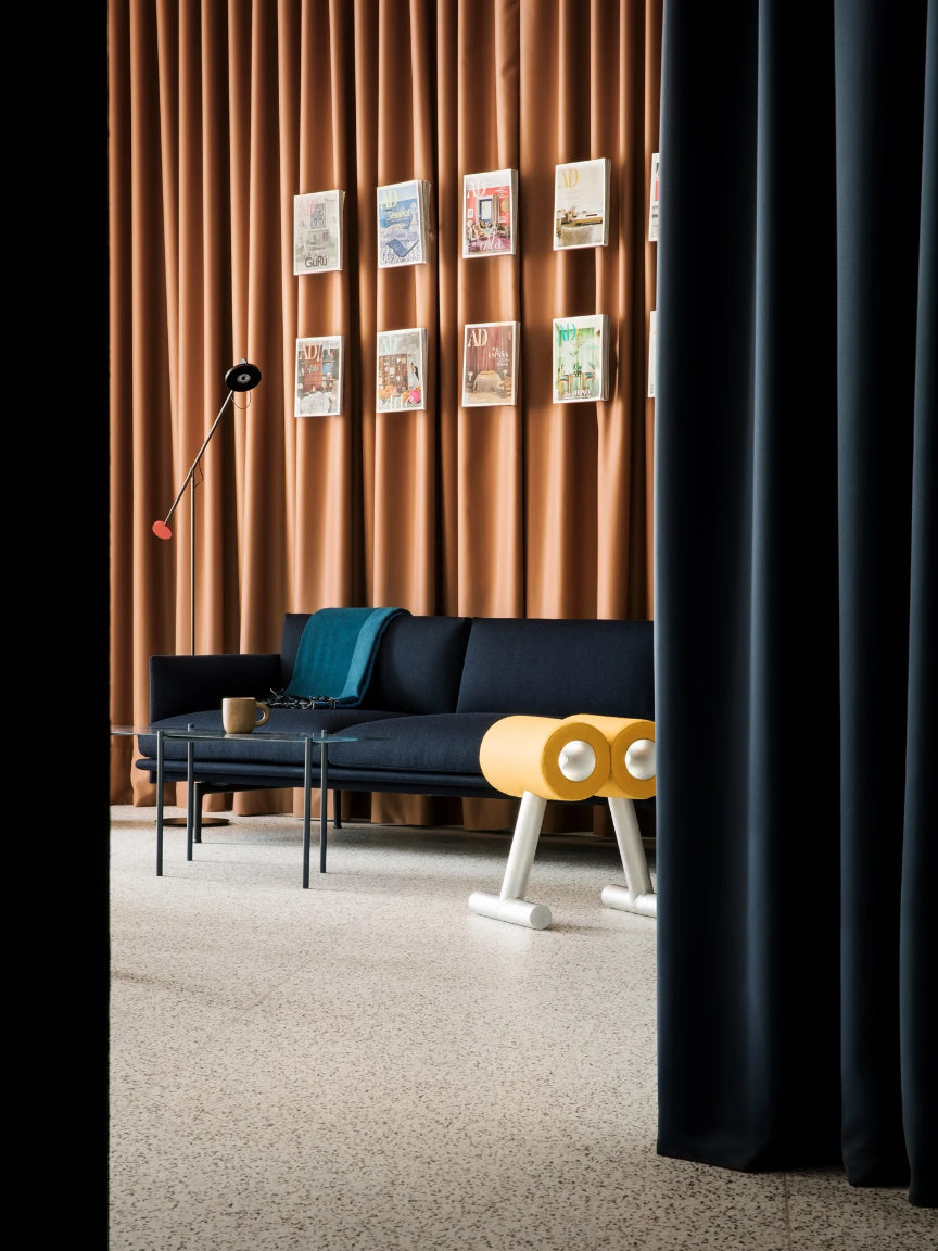 Modern interior with a black sofa, yellow side table, and decorative wall art.