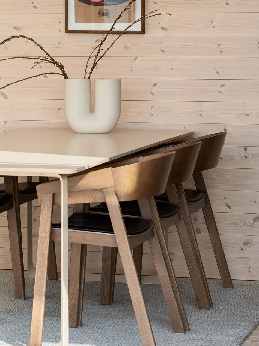 Wooden dining table with chairs against a wooden wall.