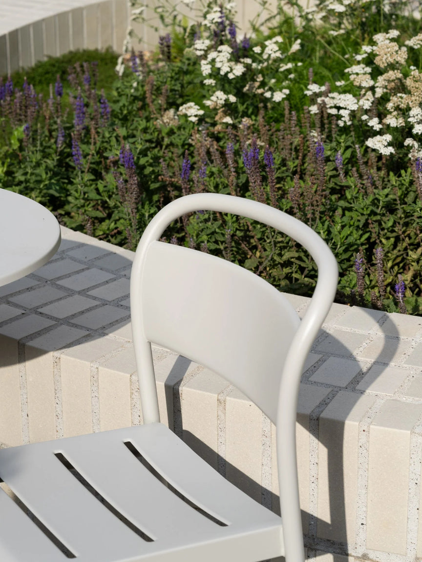 White metal chair on a patio with flowers in the background