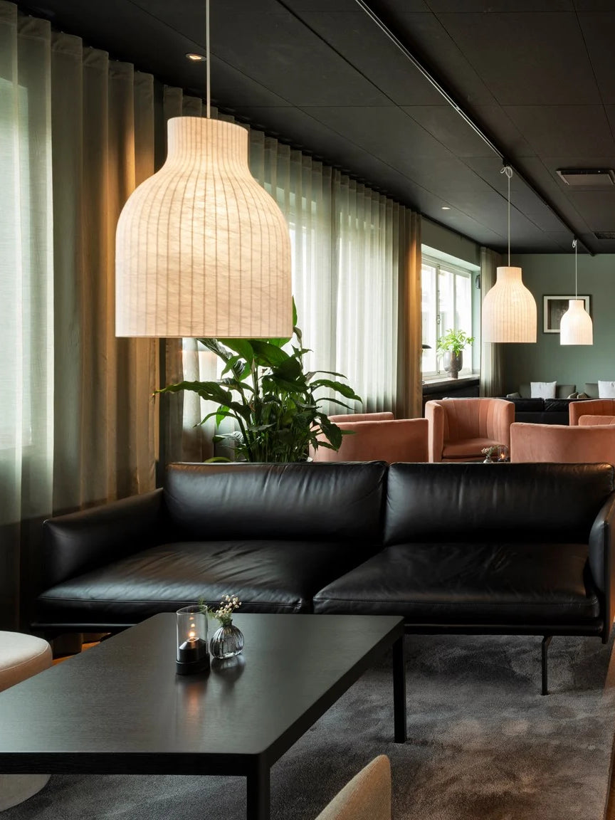 Modern interior with a black leather sofa, coffee table, and pendant lights.