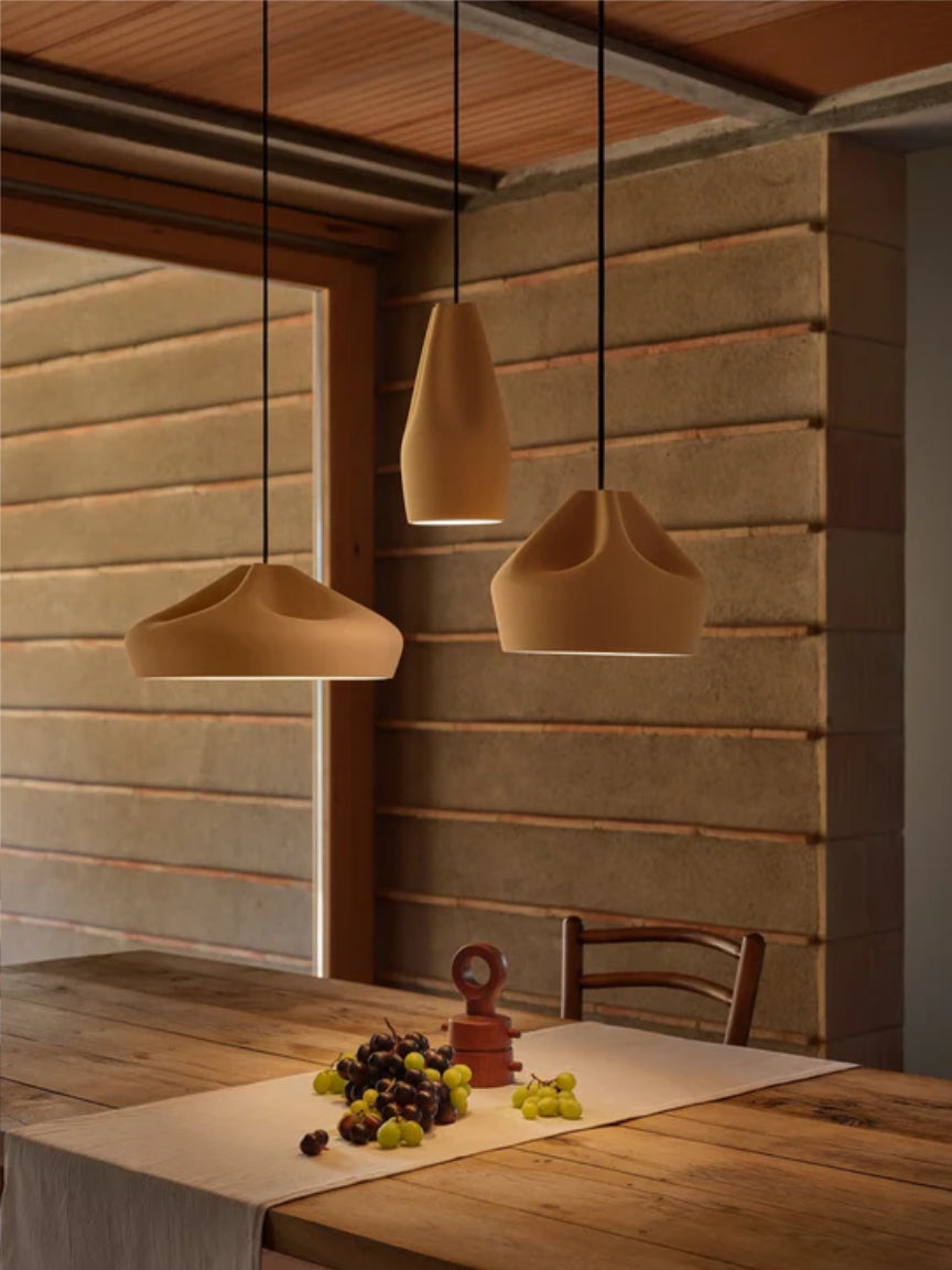 Three pendant lights hanging above a wooden table with a rustic wall background