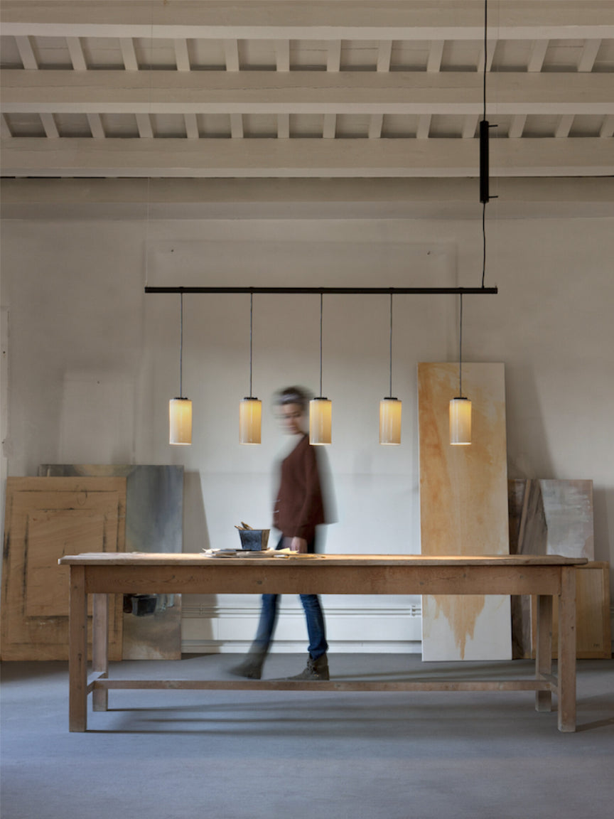 Modern interior with wooden table and pendant lights, blurred person in the background