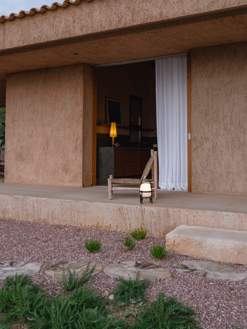 Modern house exterior with open door, interior visible, and outdoor area with plants.