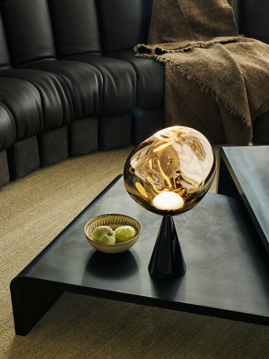 Modern interior with a black leather sofa, glass coffee table, and decorative items.