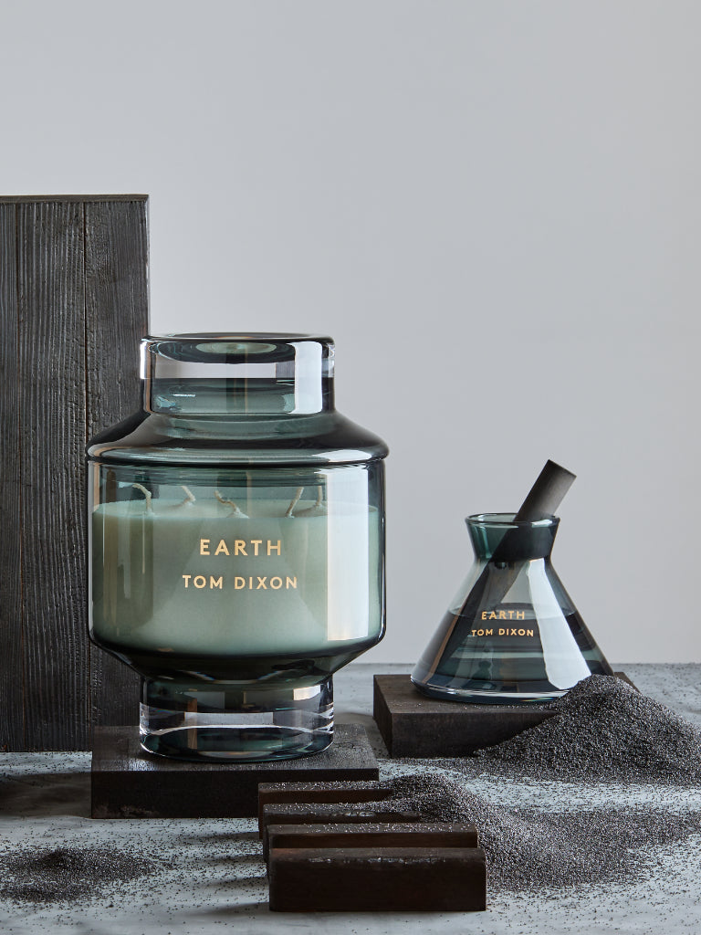 Tom Dixon candle with a decorative container on a gray surface