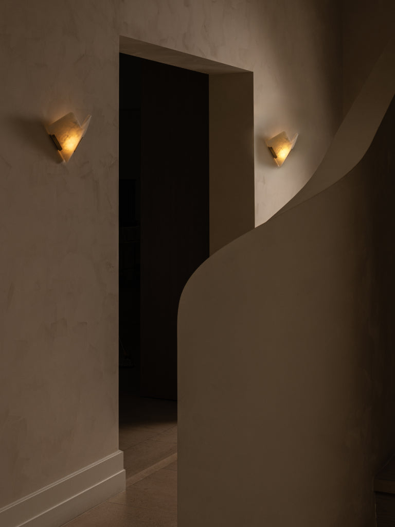 Dark room with a large open doorway and wall lights casting shadows.